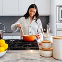 Woman stirring food in pot on stove top. 