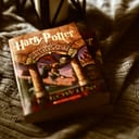 "Harry Potter and The Sorcerer's Stone" book lying on bed