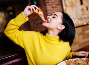 A woman enjoying a slice of pizza in a restaurant 