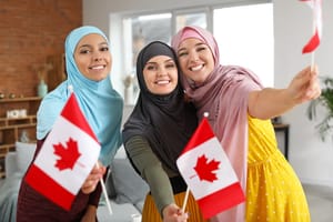Three muslim woman holding small Canadian flags