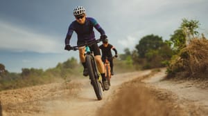 Two men riding mountain bikes down a dirt path