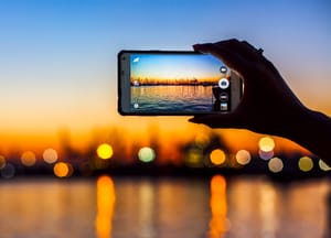 Tourist taking a picture of the wonderful sunset over the harbor