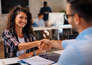 A man shaking a woman's hand at the office.