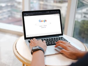 A man doing a Google search on his laptop while sitting at a coffee table