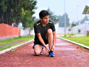 A young man tying his shoelace on a running track