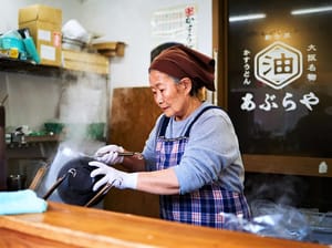 A senior woman cooking Raman at Shinsekai, Osaka, Japan
