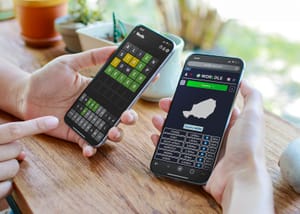 A closeup of two people holding phones with Wordle and Worldle apps opened on each