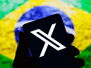 smartphone displays the X (Twitter) logo with the Brazilian flag in the background