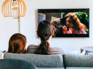 Over the shoulder shot of mother and daughter watching TV