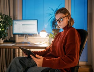 A woman wearing glasses and looking attentively at a screen.