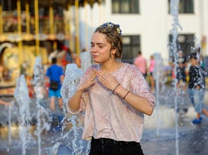 A girl playing with fountain water jets at the square in Kyiv, Ukraine, June 5, 2018.  