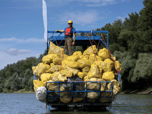 A volunteer stands on top of a pile of rubbish collected that day while participating in the Plastic Cup event near Tiszaroff, Hungary, Aug. 2, 2023.