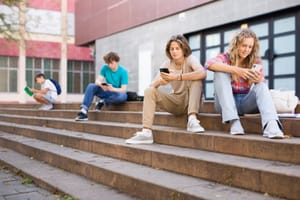Teenagers sitting on steps using their phones