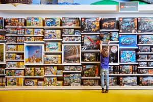 Boy reaches for a LEGO set in a shop.