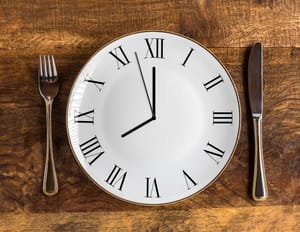 a clock on a plate with knife and fork on the sides