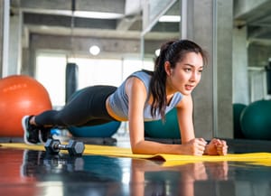 a fit woman holding a plank position on a yoga mat