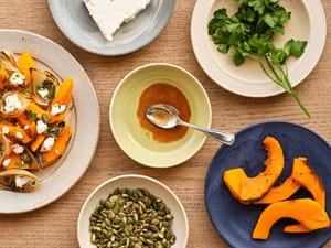 Roasted pumpkin and onion with Vinaigrette served on a wooden table.