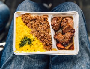 Chicken and pork served with mashed potatoes and vegetables in a plastic container.
