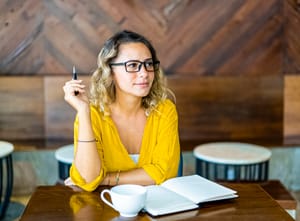 Girl holding a pen, thinking, and getting ready to write something 