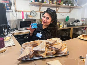 Gabriela Rodriguez holds a can of tuna in front of a pile of tuna sandwiches. 