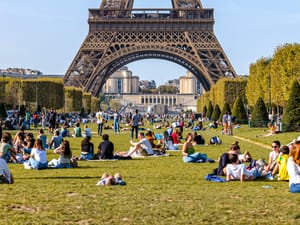 People sitting on the ground in Paris in front of the Eiffel Tower