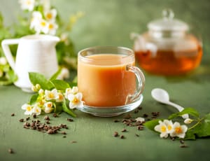 A cup of Jasmine milk tea and flowers on green background