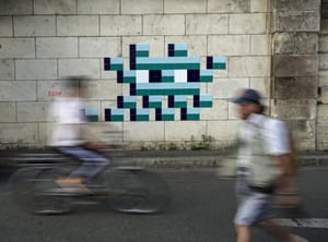 A cyclist rides in front of an Olympic-themed new mosaic by the mysterious French street artist known only by the name Invader, Wednesday Aug. 7, 2024, on the banks of the Seine River, during the 2004 Summer Olympics, in Paris, France. 
