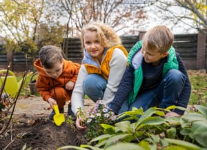 Kids planting flowers in a garden.