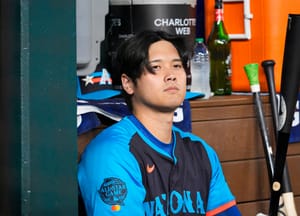 National League's Shohei Ohtani, of the Los Angeles Dodgers, sits in the dugout during the first inning of the MLB All-Star baseball game, Tuesday, July 16, 2024, in Arlington, Texas.