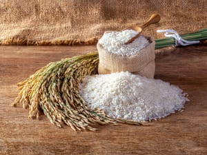 A rustic setting with a sack of uncooked white rice spilling out onto a wooden surface