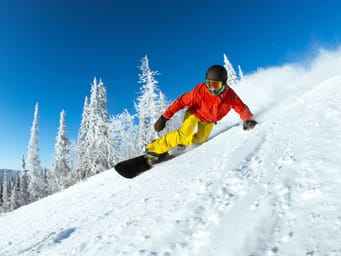 A snowboarder sliding rapidly down a ski slope, captured in a dynamic winter sports photo.