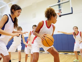 A female high school basketball team playing a competitive game on the court.