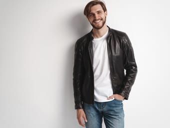 A male model wears a leather jacket against a white background.