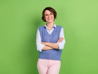 A photo portrait of a young business woman smiling with crossed hands.
