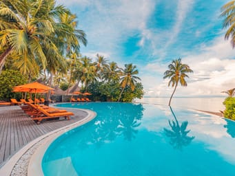Stunning landscape, swimming pool blue sky with clouds. Tropical resort hotel in Maldives. Fantastic relax and peaceful vibes, chairs, loungers under umbrella and palm leaves. Luxury travel vacation