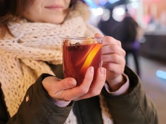 Close-up mug with mulled wine in a woman's hands. 
