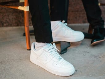A person in black pants and white Nike sneakers.