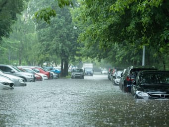 Flooded cars on a city street after heavy rain, highlighting the risk of water entering the engine, transmission parts, or other components.