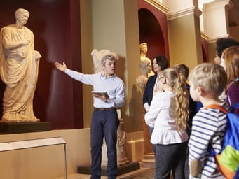 Pupils And Teacher On School Field Trip To Museum With Guide