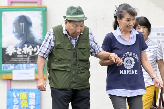 Iwao Hakamada, left, 88-year-old former boxer who has been on death row for nearly six decades after his murder conviction that his lawyers said was based on forced confession and fabricated evidence, is helped by a supporter as he goes for a walk in Hamamatsu, Shizuoka prefecture, central Japan Wednesday, Sept. 25, 2024.